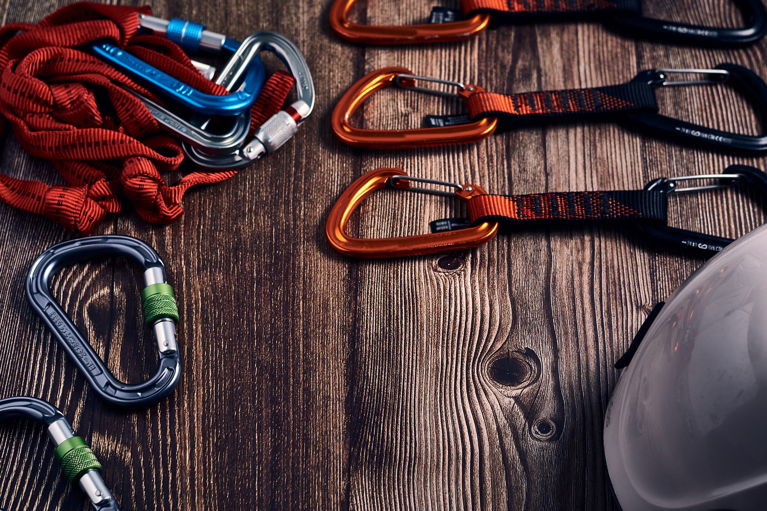 Closeup shot of many colorful climbing carabiners and knots on a wooden surface